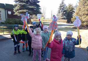 Dzieci z wiosennymi symbolami i emblematami przez budynkiem przedszkola